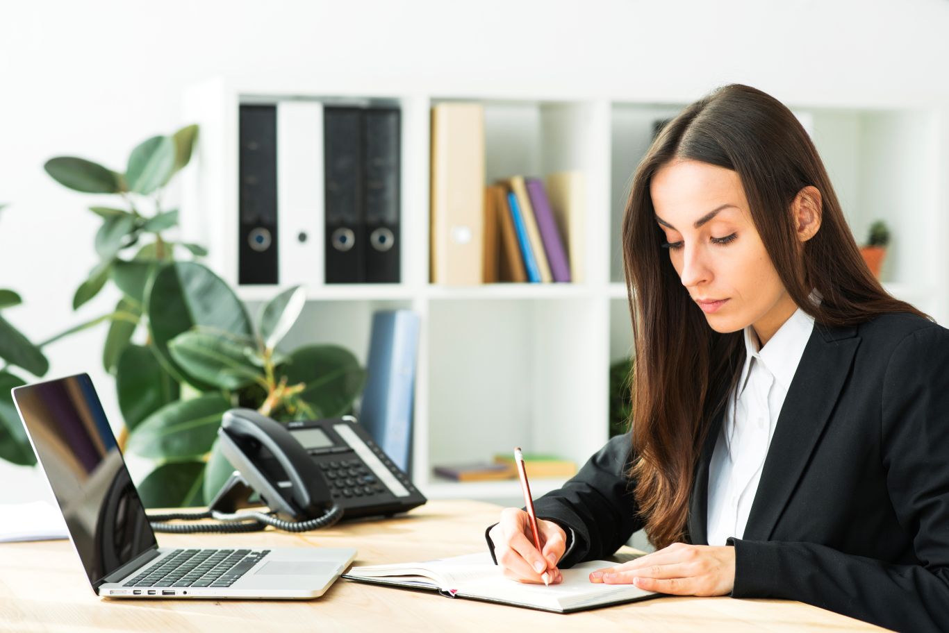 beautiful-young-businesswoman-writing-with-pencil-diary-with-laptop-desk